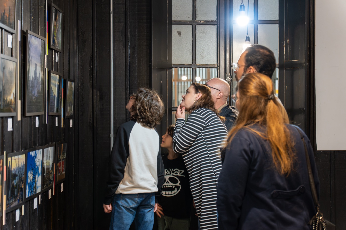 Público observa as fotografias da exposição Cidade, Cor e Ambiente penduradas na parede da Galeria Estação da Arte, em Passo Fundo.